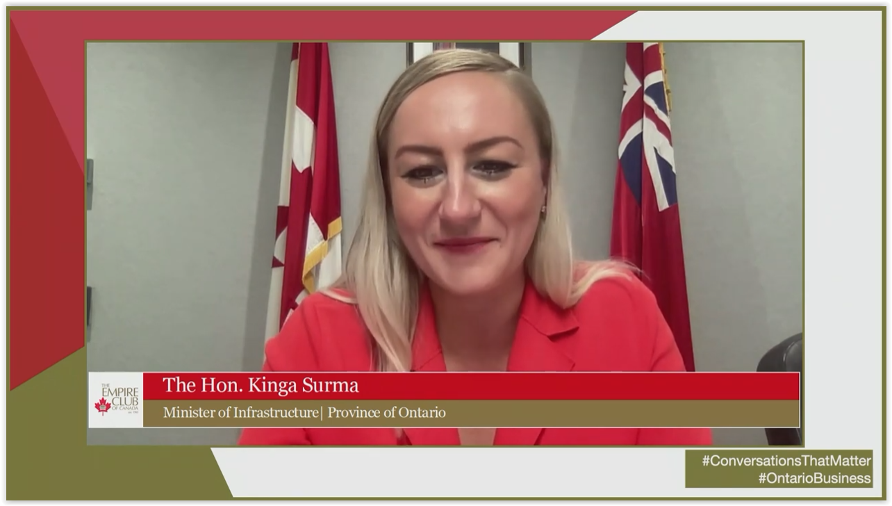 screenshot of Minister Surma presenting virtually with two flags behind her