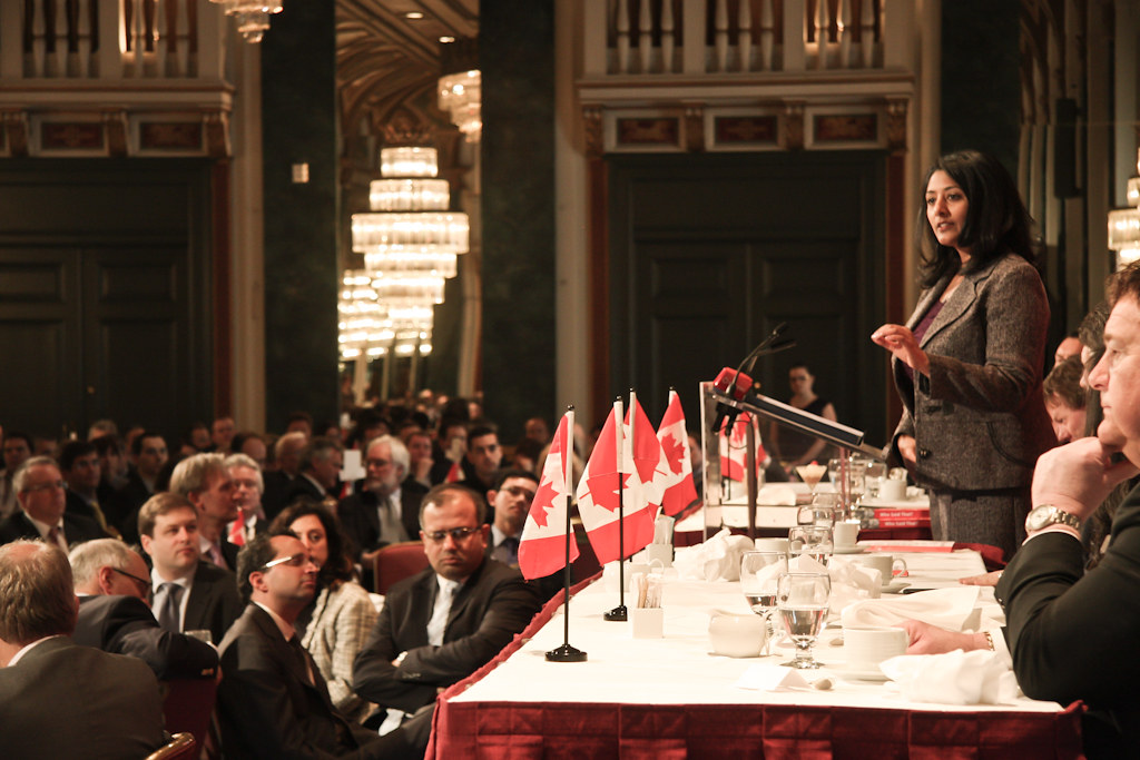 a woman speaking to a crowd in a grand hall