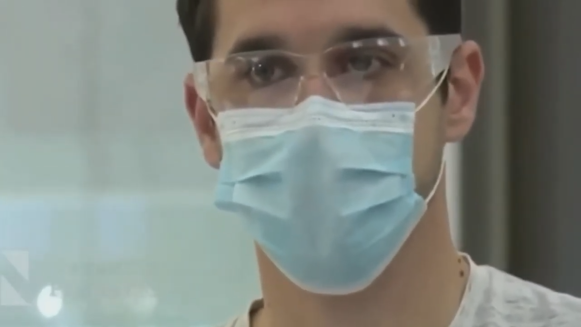 A man wearing a surgical face mask and eye goggles