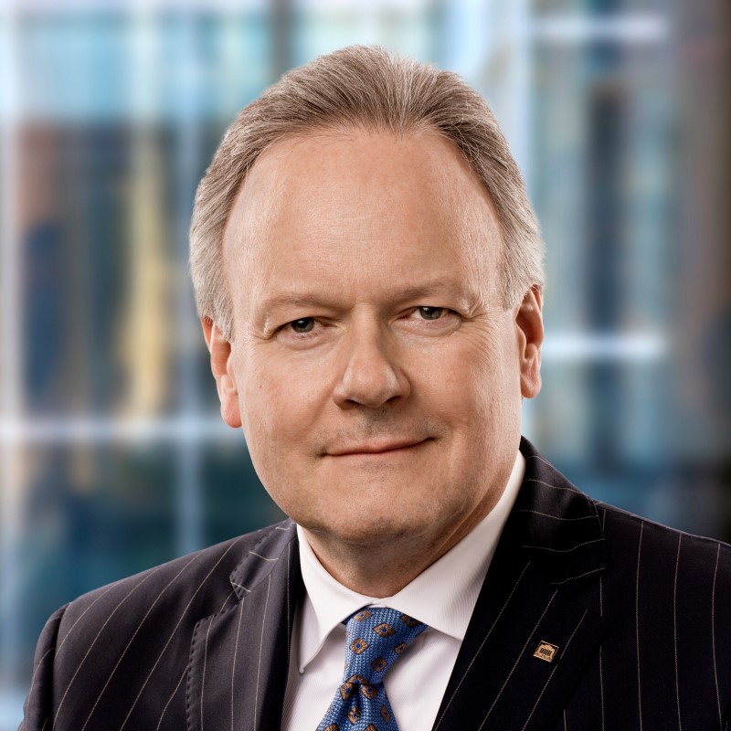 A man, Stephen-Poloz, in black jacket and blue tie, smiling