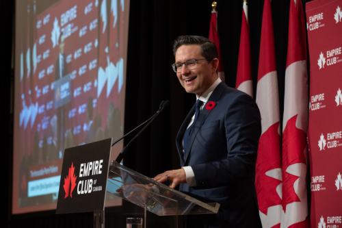 Pierre Poilievre in black suit is smiling during the keynote speech at Empire Club of Canada