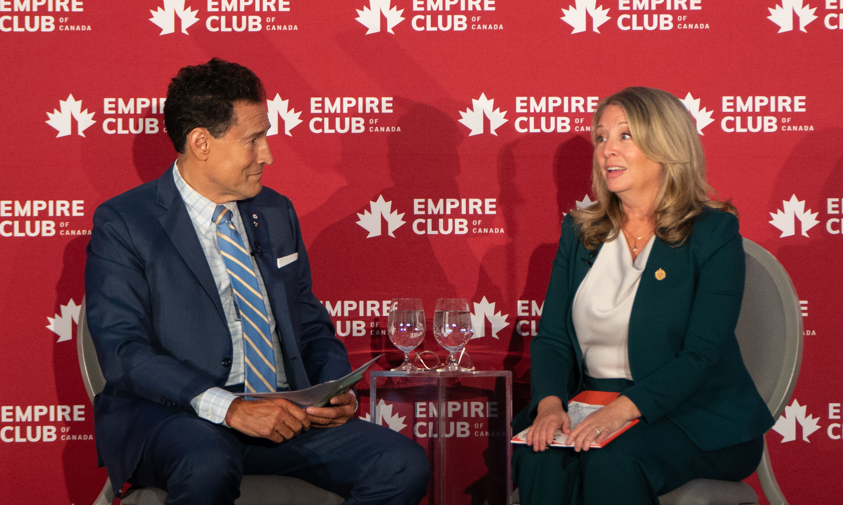 A man and a woman talking with each other at the stage of Empire Club of Canada